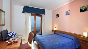 Une chambre d’hôtel avec un lit, un bureau équipé d’un ordinateur, une chaise et une vue sur l’extérieur.