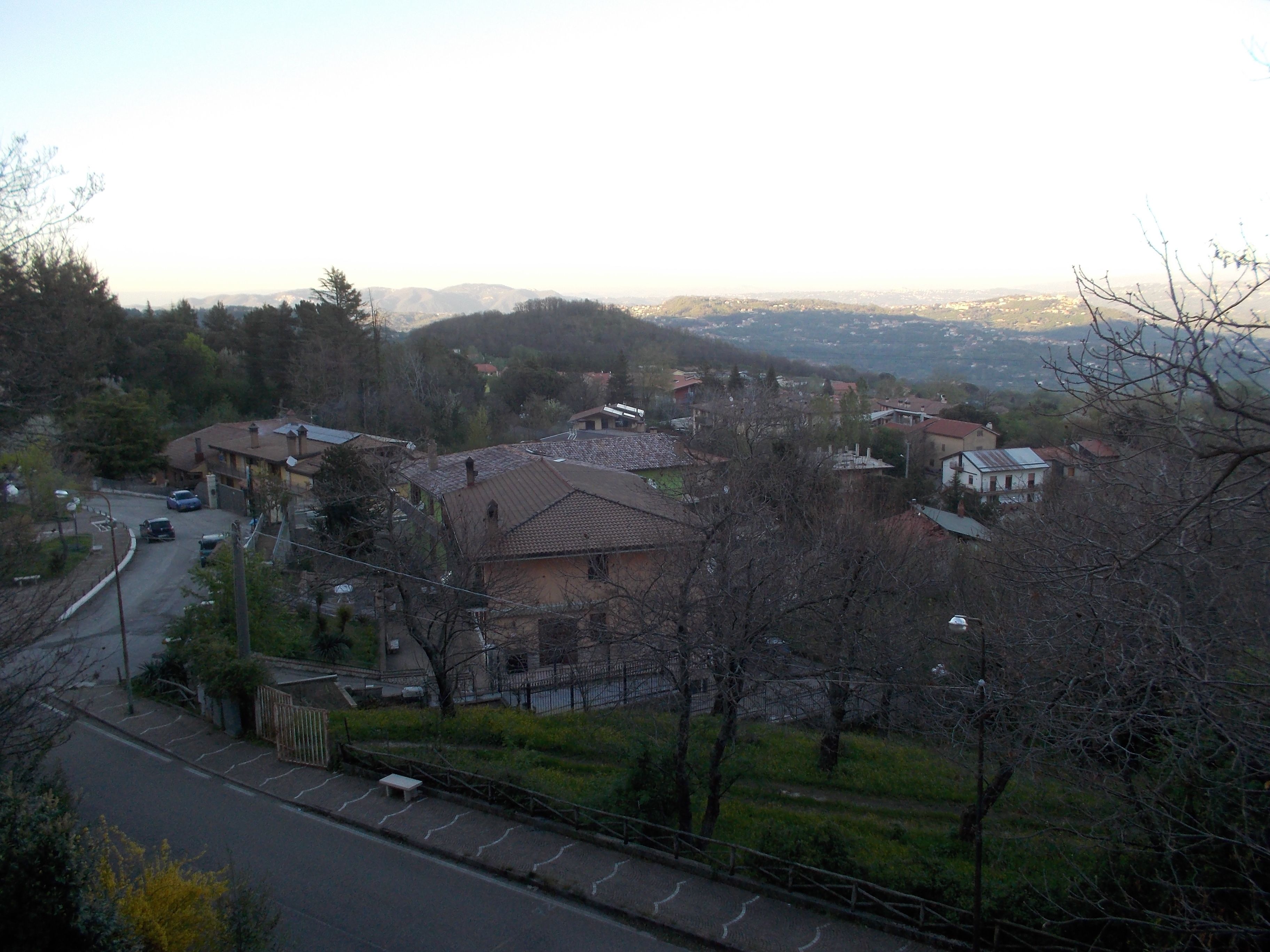 Zona residencial com casas, uma estrada e vista para montanhas ao longe.