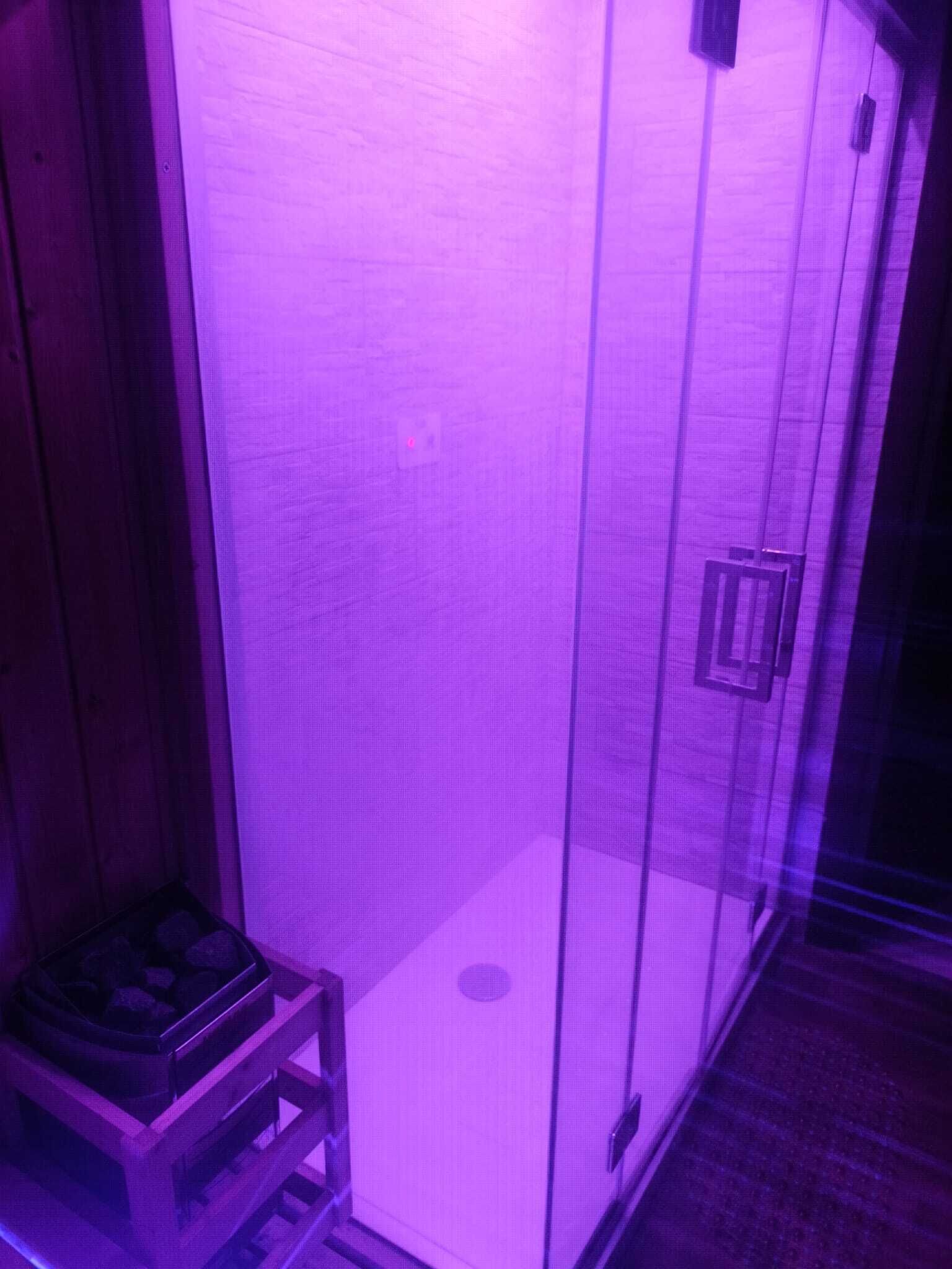 A room with a purple-lit cabinet, a small wooden stool, and a door with a handle.