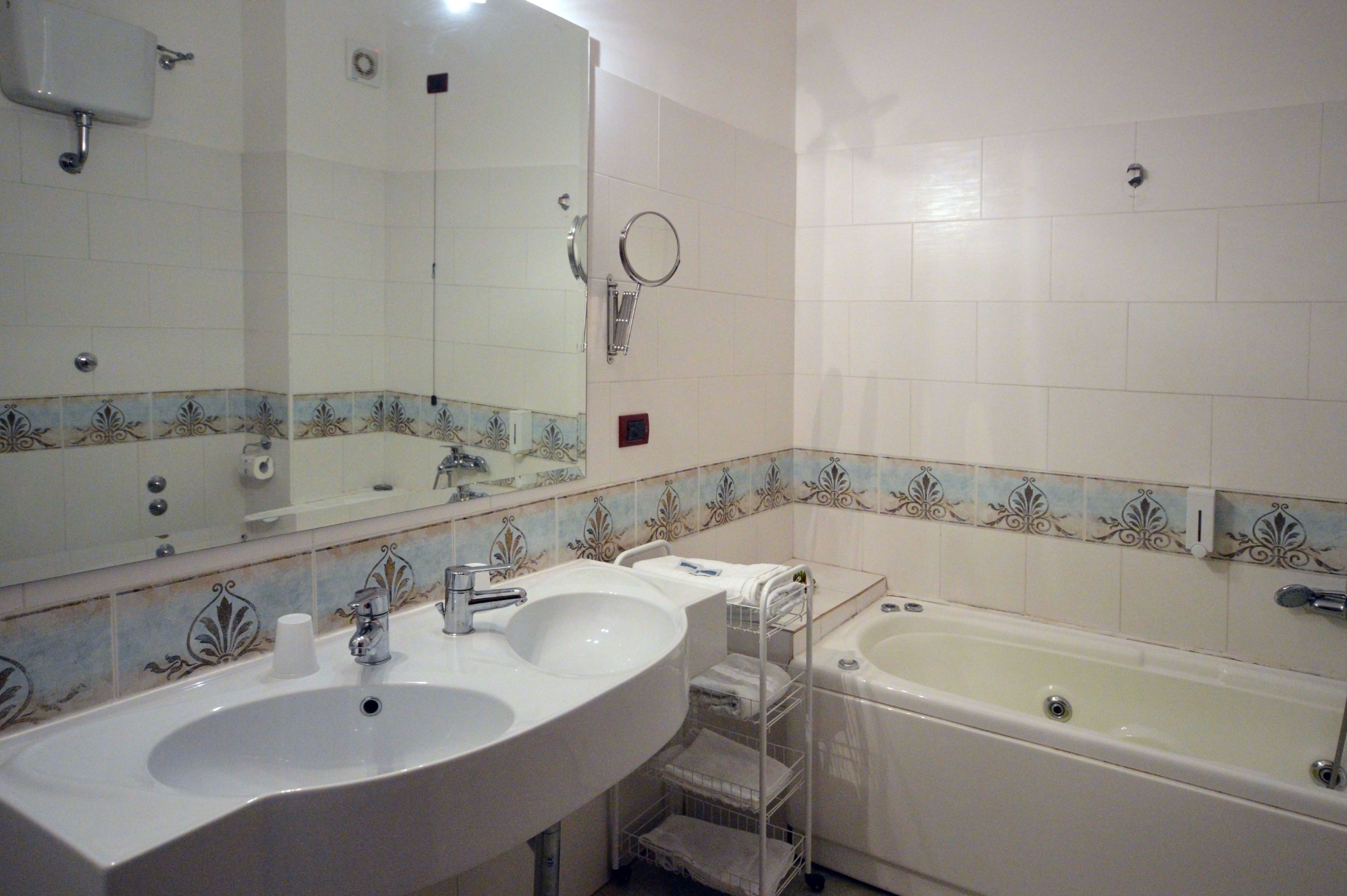 Un bagno con due lavandini, una vasca e uno specchio grande.