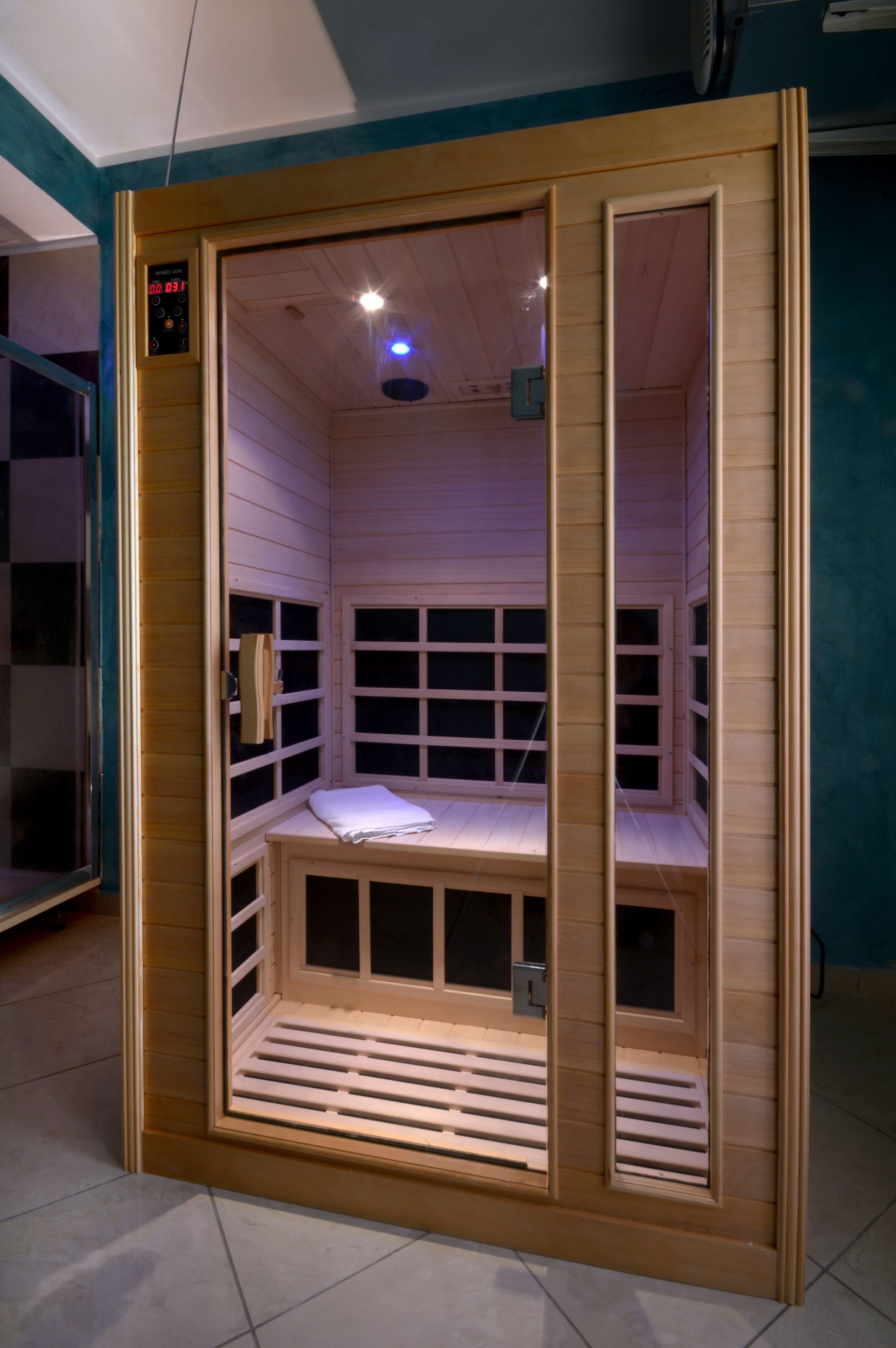 A wooden sauna with a digital timer, a bench, and a window.