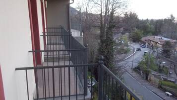 Ein Wohngebäude mit Balkon, einer Treppe und Blick auf eine Straße mit parkenden Autos und Häusern.