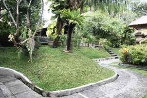 Un sendero de jardín con un diseño curvo de piedra, rodeado de abundante follaje y diversas plantas.