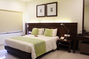 Una camera d'albergo ordinata con un letto grande, comodini, una scrivania e una sedia.