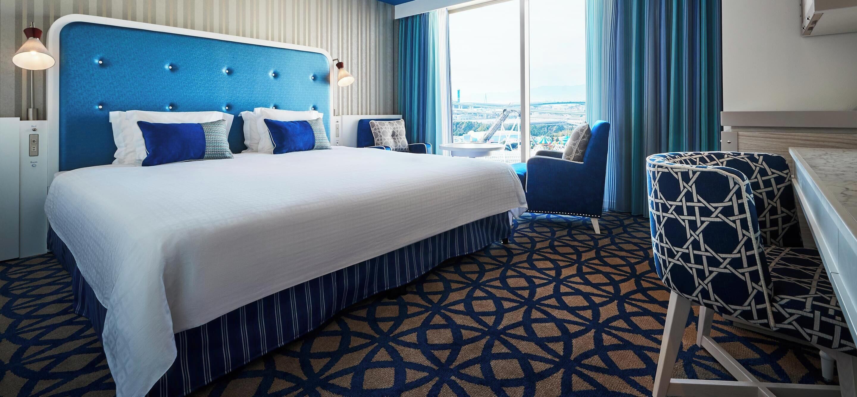Een hotelkamer met een groot bed, een zithoek en uitzicht op de stad.