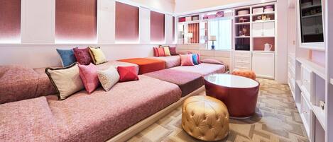 A modern living room with a sofa set, ottomans, and a glass coffee table.