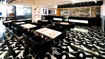 A restaurant with black and white patterned flooring, tables with 'BR' signs, and a bar area in the background.