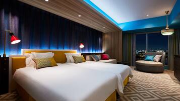 Een hotelkamer met een groot bed, een bank en uitzicht over de stad.