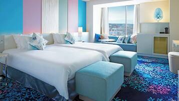 Habitación de hotel con dos camas, un sofá, una mesita, un televisor y vistas a la ciudad.