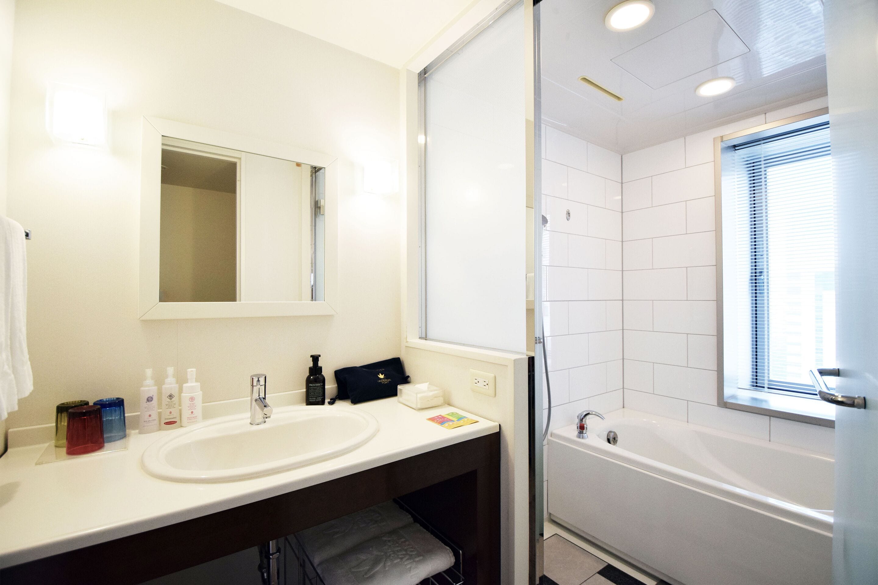 A bathroom with a sink, mirror, and bathtub.