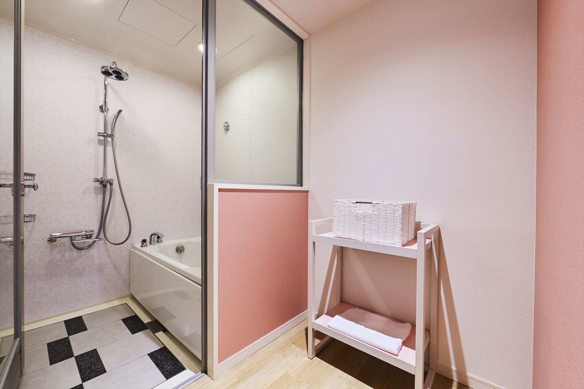 A bathroom with a glass shower enclosure, a white bathtub, and a white shelf with a basket.
