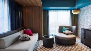 Ein modernes Hotelzimmer mit einer Couch, einem Hocker und einem runden Tisch.
