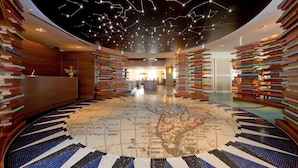 Eine Lobby mit einem zentralen Teppichbereich, Holzsichtwänden und einem Design der Decke, das Sterne darstellt.