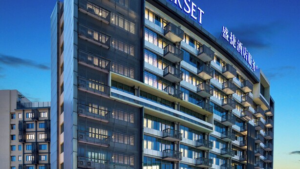 Een modern hotel met meerdere verdiepingen, balkons en een opvallend naamteken.