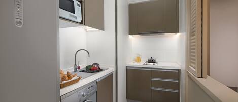 A compact kitchen with a washing machine, a microwave, and a sink.
