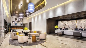 Un vestíbulo moderno con un mostrador de recepción, una zona de estar y un techo decorativo.