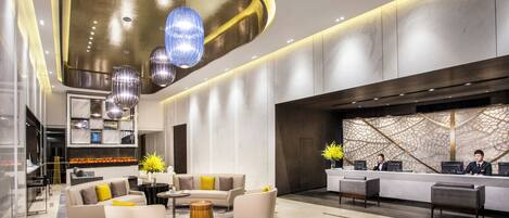 A modern lobby with a reception desk, seating area, and a decorative ceiling.