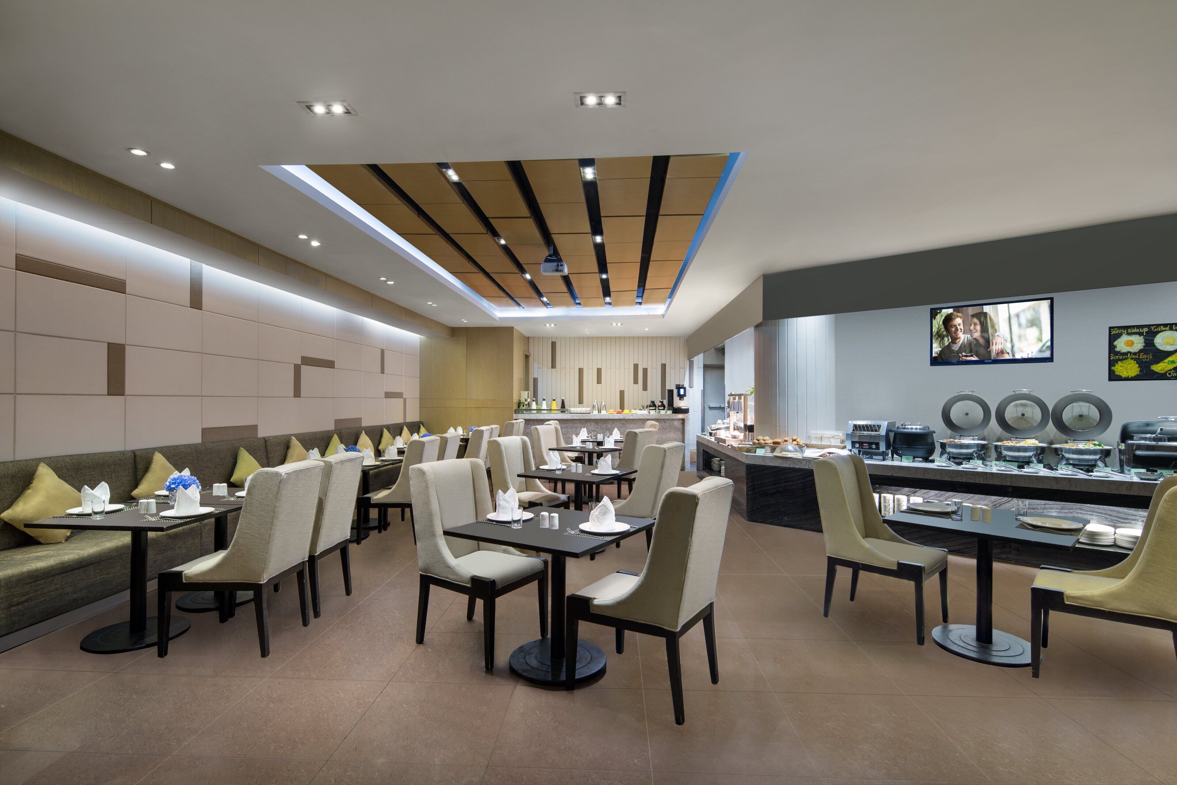 A modern restaurant with a long counter, multiple tables, and chairs.