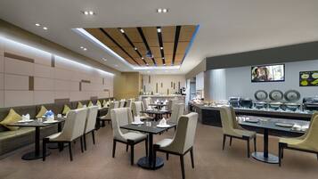 A modern restaurant with a long counter, multiple tables, and chairs.
