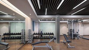 Un gimnasio moderno con equipo de levantamiento de pesas, bancos y mancuernas.