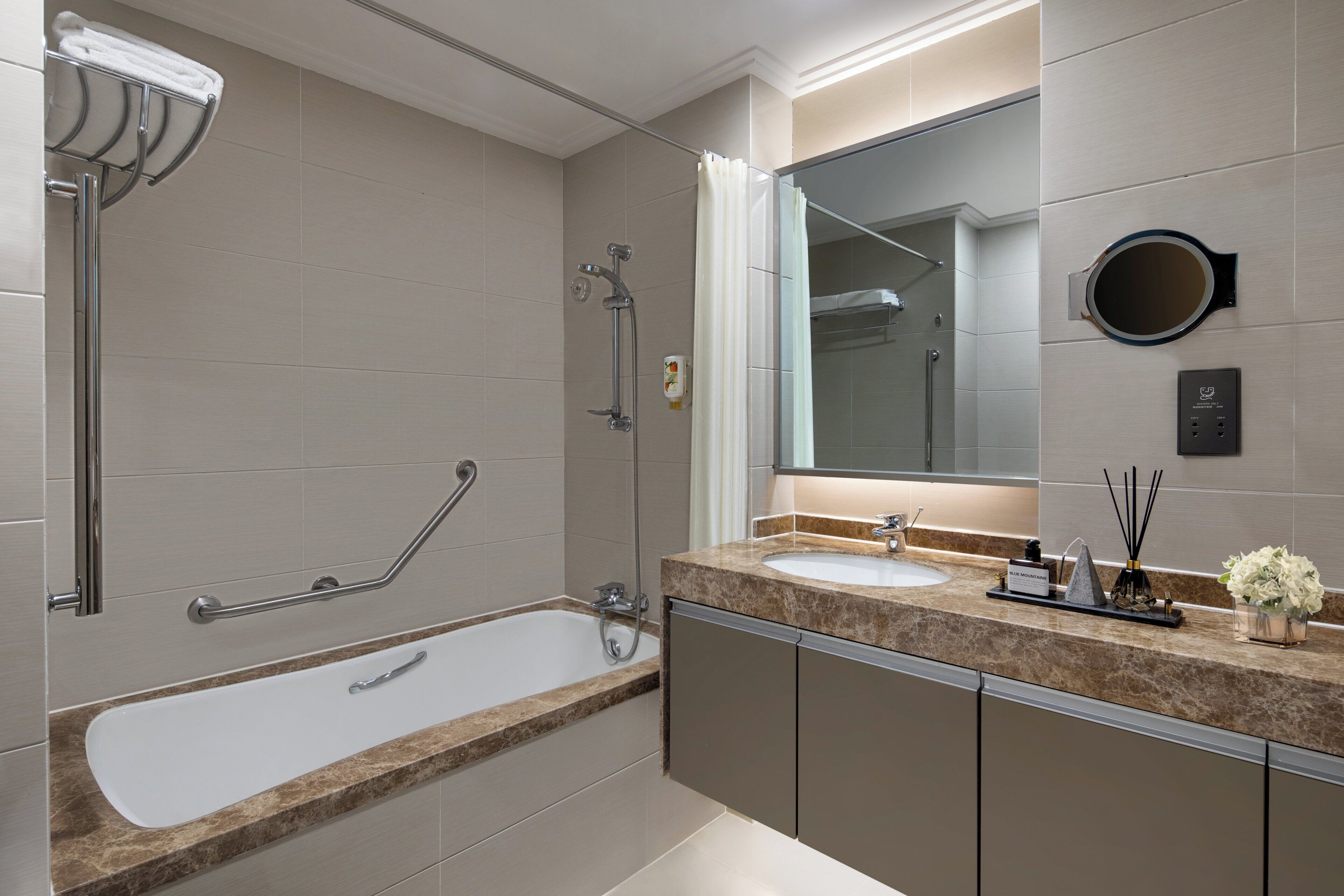 Un baño moderno con bañera, lavamanos y un espejo grande.