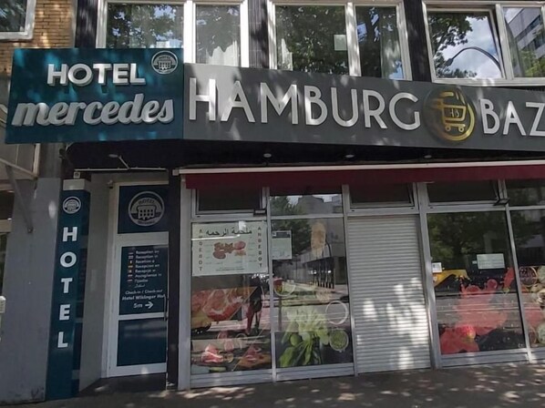 A hotel with a sign for 'Hotel Mercedes Hamburg' and a storefront with a shuttered window. - Hotel Mercedes Hamburg (Hamburg)