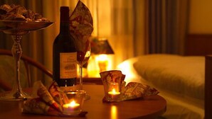 A hotel room with a bed, a bedside table with a bottle of wine, a candle, and a glass. - Hotel Mercedes Hamburg (Hamburg)