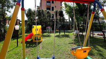 Children can play on the swings in the hotel's grassy playground.