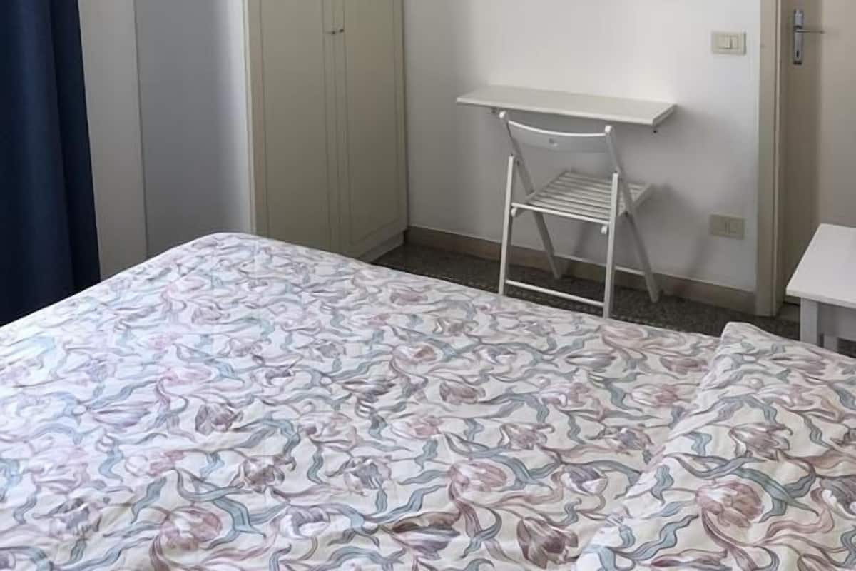 A bedroom with a bed, a wardrobe, a desk, and a chair.
