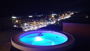 Ein Whirlpool mit Blick auf eine beleuchtete Stadt bei Nacht.
