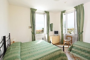 A bedroom with two beds, a dresser, a chair, and a TV. - Arianna Hotel (Pietrasanta)