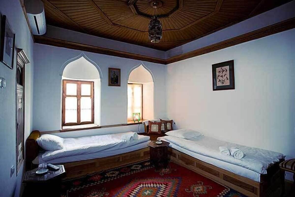 Une chambre avec deux lits simples, un plafond en bois et un tapis à motifs.