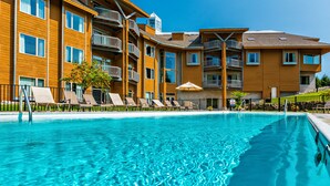 Una piscina con sillas de descanso y un edificio de madera con balcones.