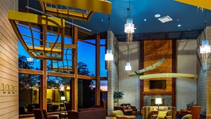 Un vestíbulo espacioso con techo alto, ventanas amplias y luminarias modernas.
