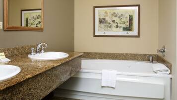 A bathroom with two sinks, a large mirror, a framed artwork, and a bathtub.