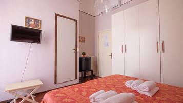 Ein Hotelzimmer mit Bett, Schreibtisch, Fernseher, Kleiderschrank und Heizkörper.