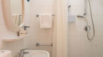 Un baño con lavamanos, espejo, ducha y toallero.