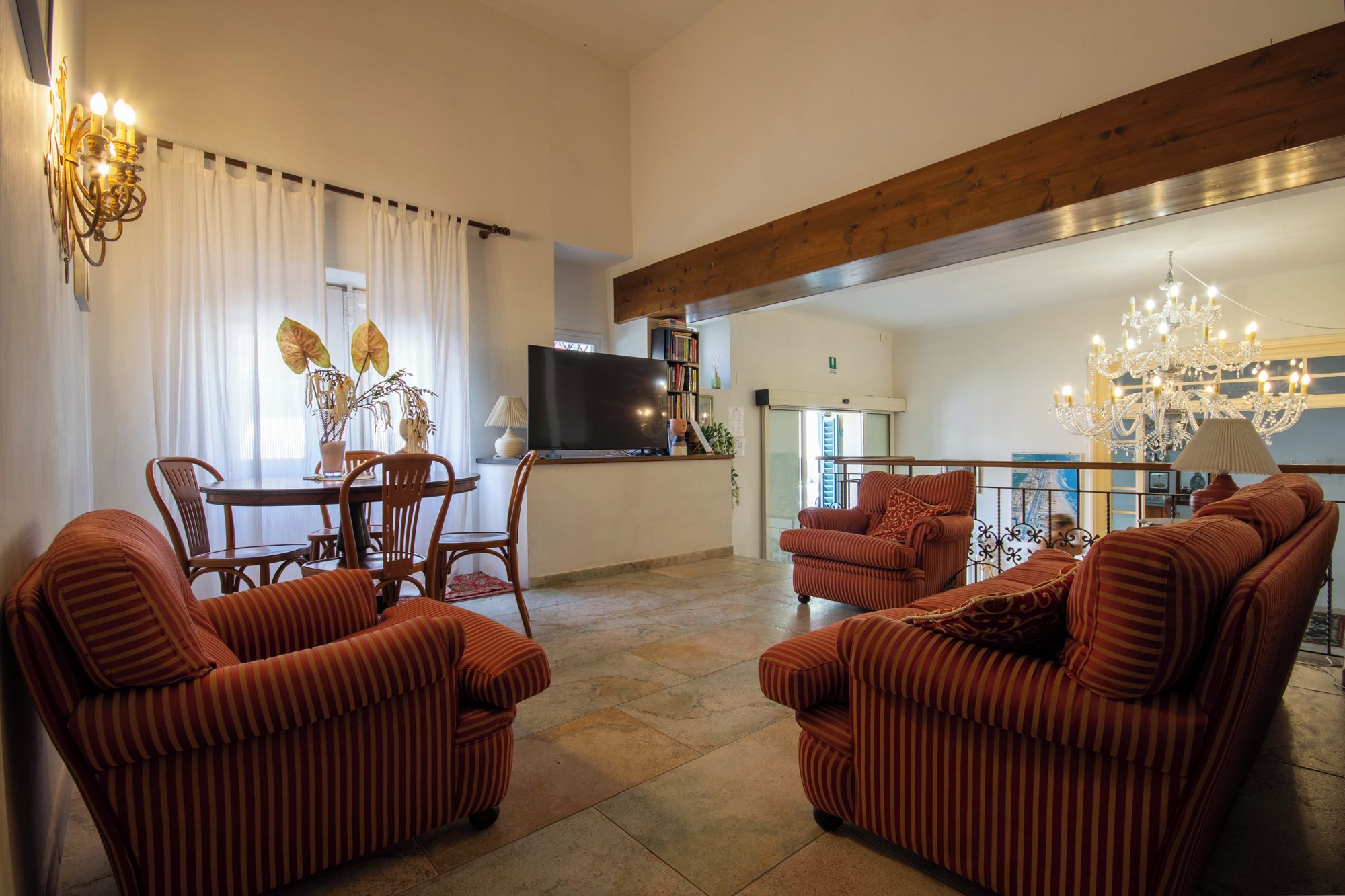 A living room with striped sofas, a dining table, and a TV.