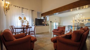 A living room with striped sofas, a dining table, and a TV.