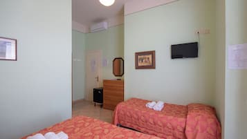 Habitación de hotel con dos camas, un aparador, un televisor y una puerta que da a otra habitación.
