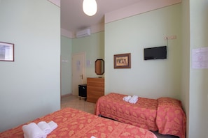 Habitación de hotel con dos camas, un aparador, un televisor y una puerta que da a otra habitación.