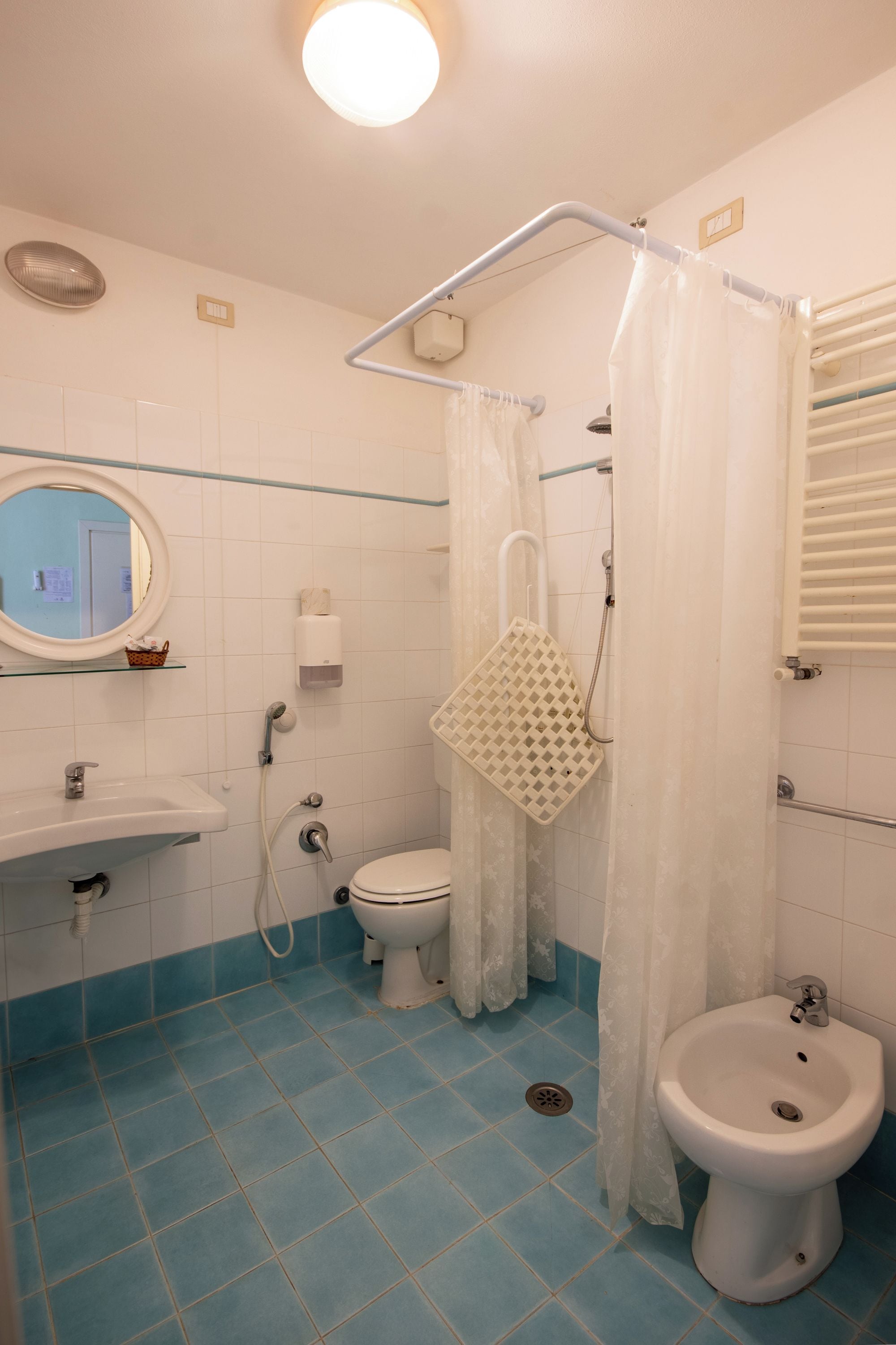 Ein Badezimmer mit Toilette, Bidet, Waschbecken und Duschbereich.
