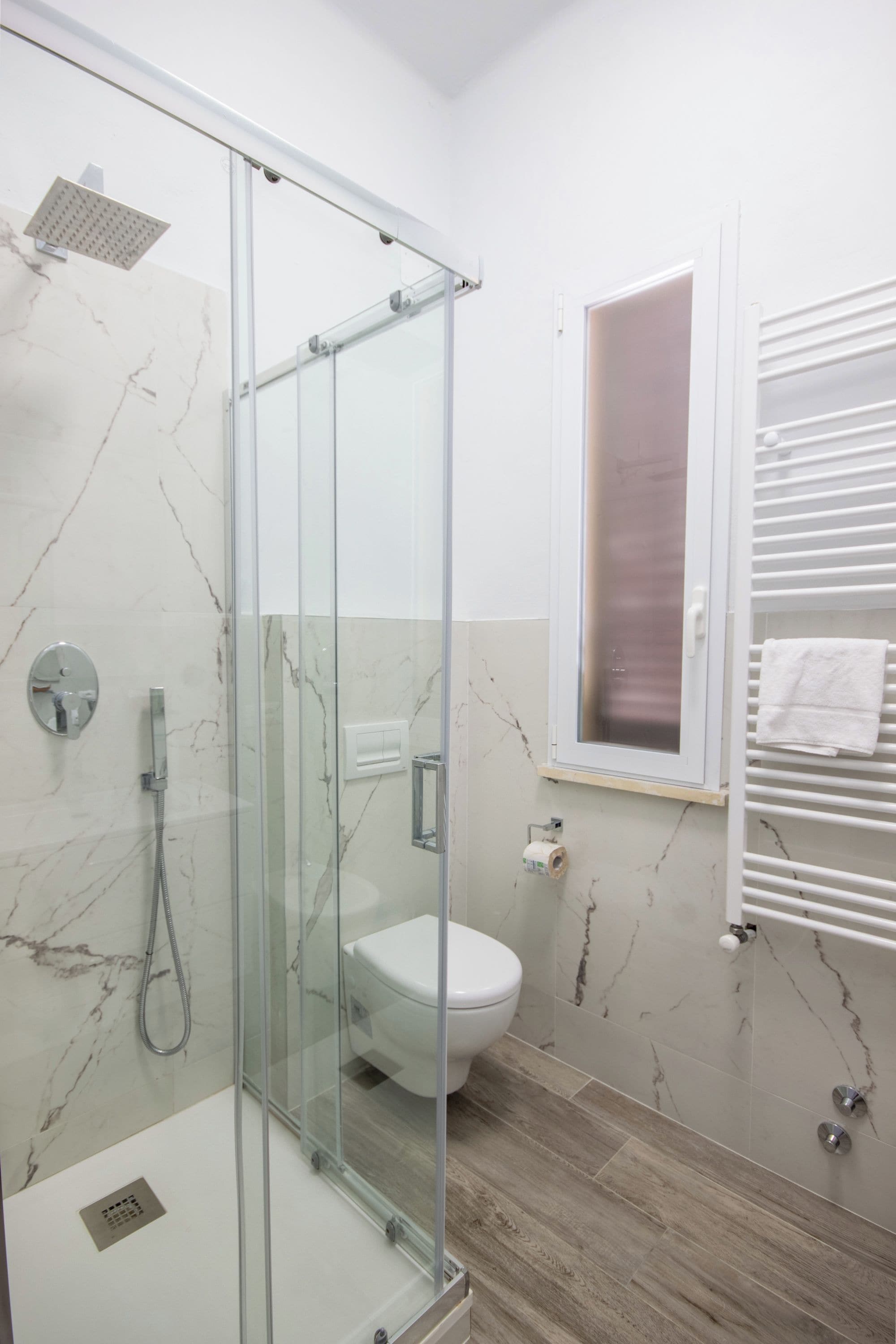 Un baño moderno con ducha de vidrio, inodoro y perchero para toallas.