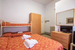Un dormitorio con literas, un armario de madera, un aparador, un televisor y un espejo.