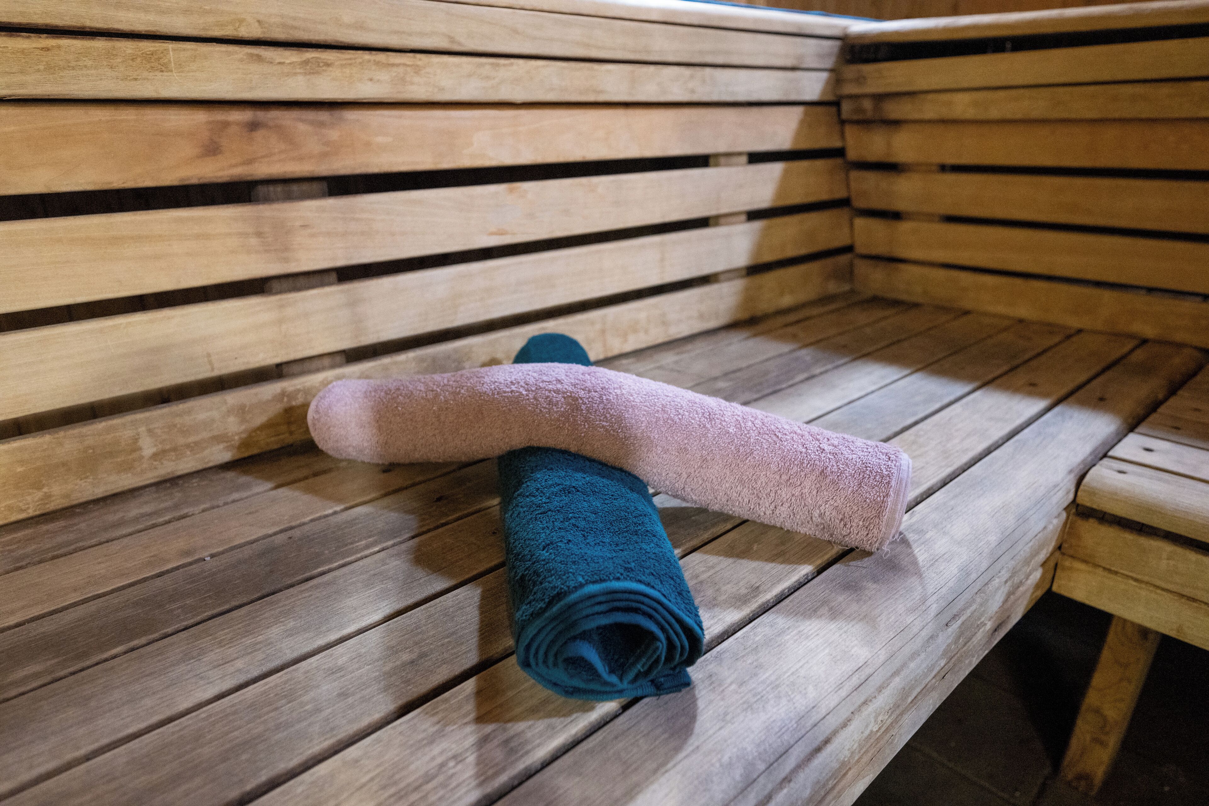 Un banco de madera con una toalla enrollada y una manta doblada.