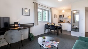 A modern hotel room with a dining area, kitchenette, and a TV. - Nemea Appart Hotel Toulouse Aéroport (Toulouse)