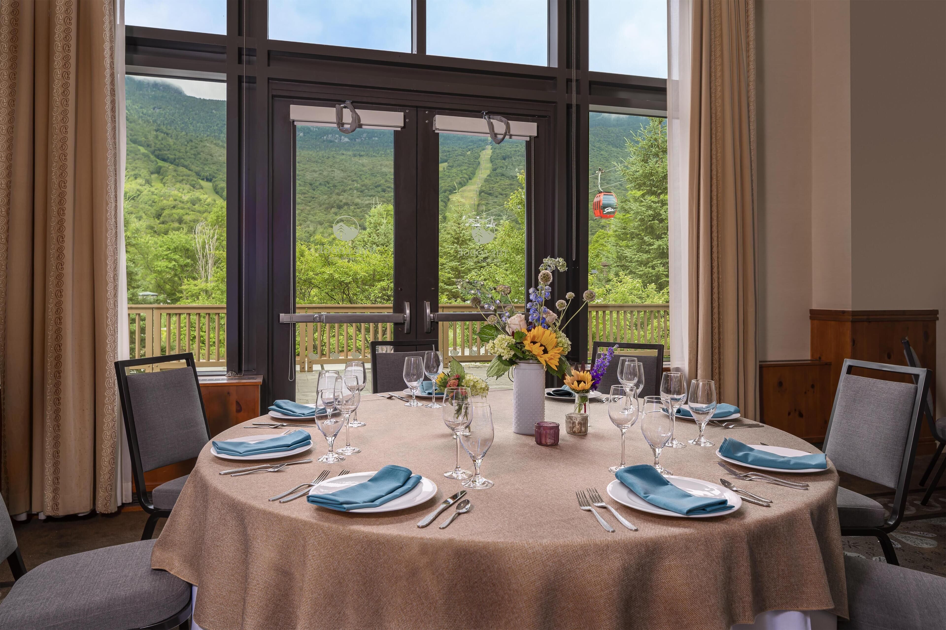 A dining table set for six with a view of a forested mountain.
