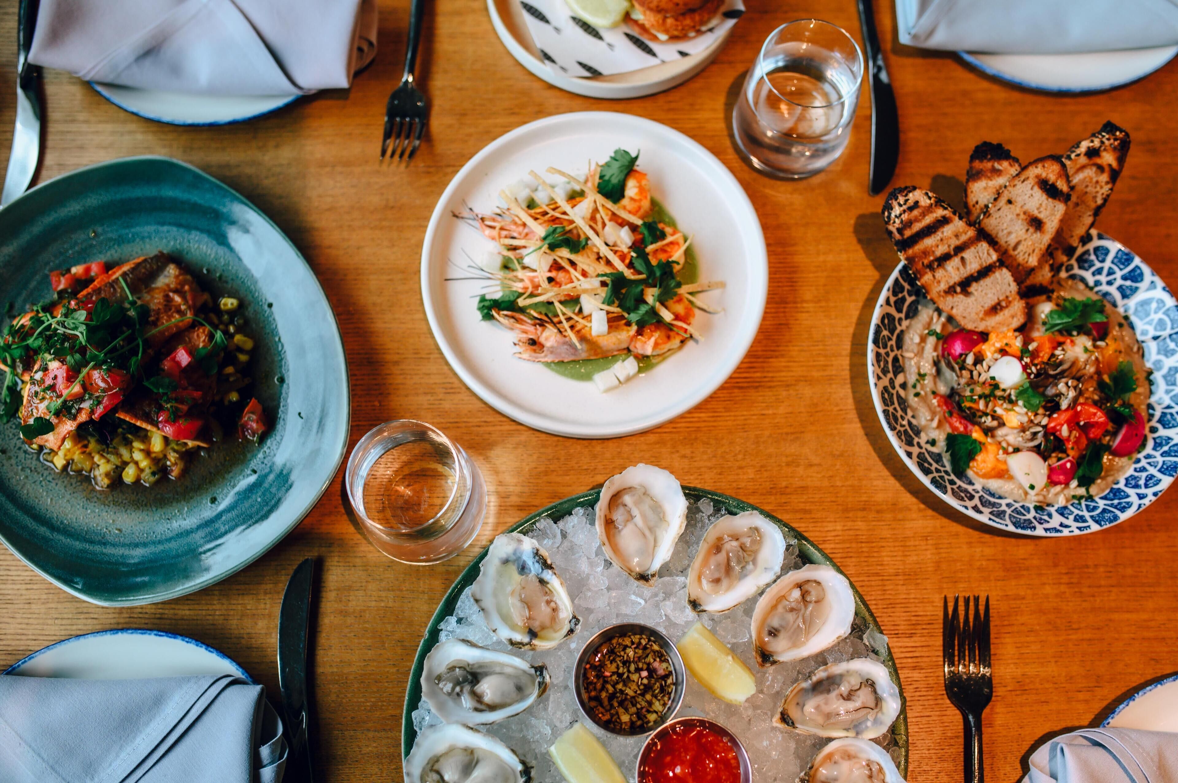A dining table with multiple plates of food, including seafood and salads.