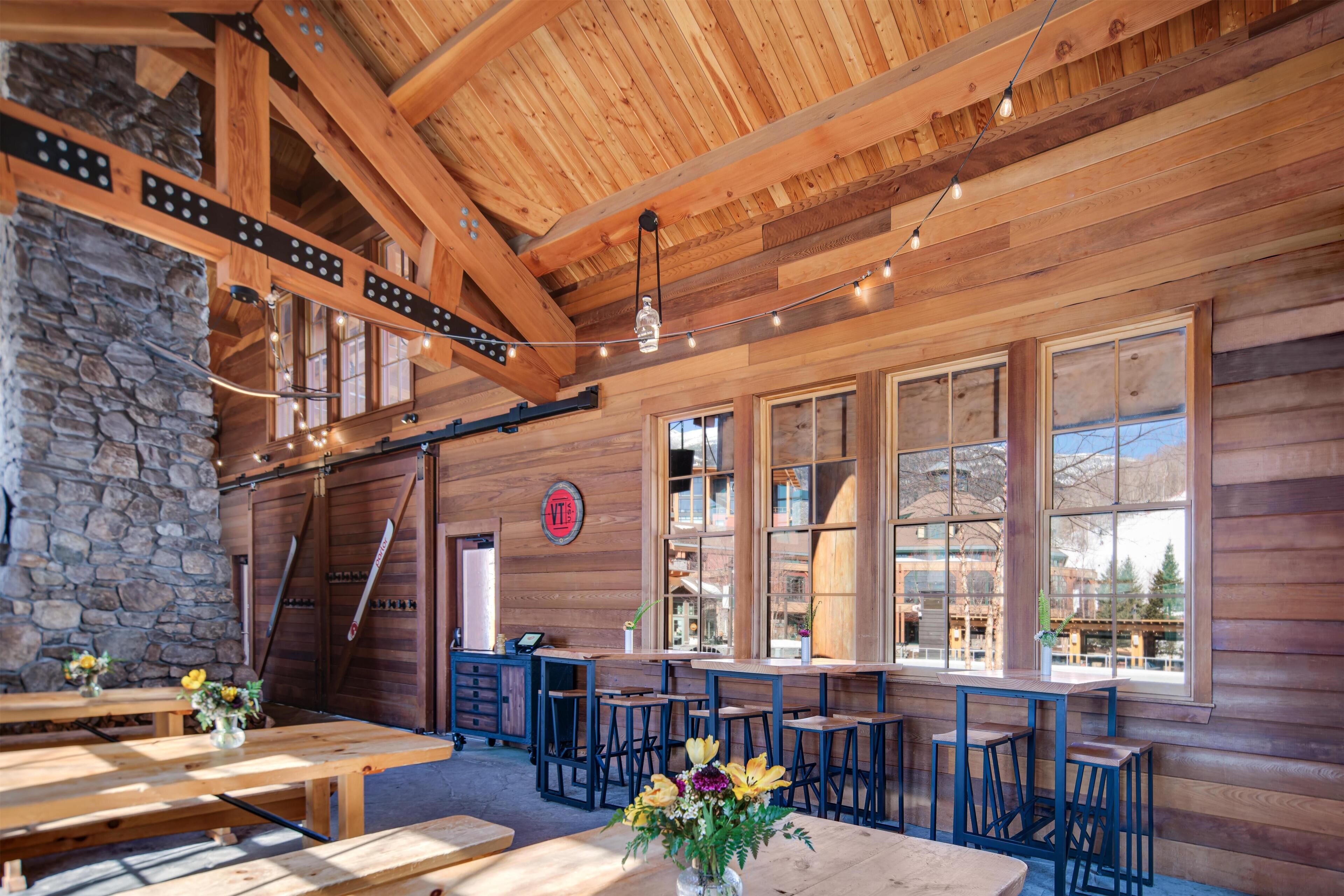 A wooden interior with stone walls, wooden beams, and large windows.