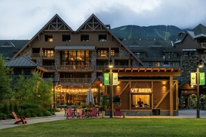 A lodge with a prominent 'Vt Beer' sign, outdoor seating, and a mountainous backdrop. - The Lodge at Spruce Peak, a Destination by Hyatt Residence (Stowe)